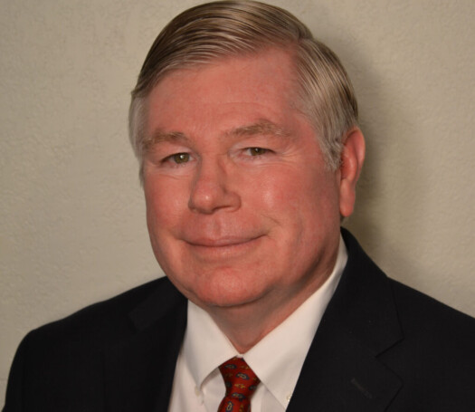 Portrait of a mature man in a suit and tie, smiling gently.
