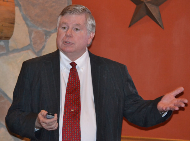 Man in suit giving a presentation with a remote control.